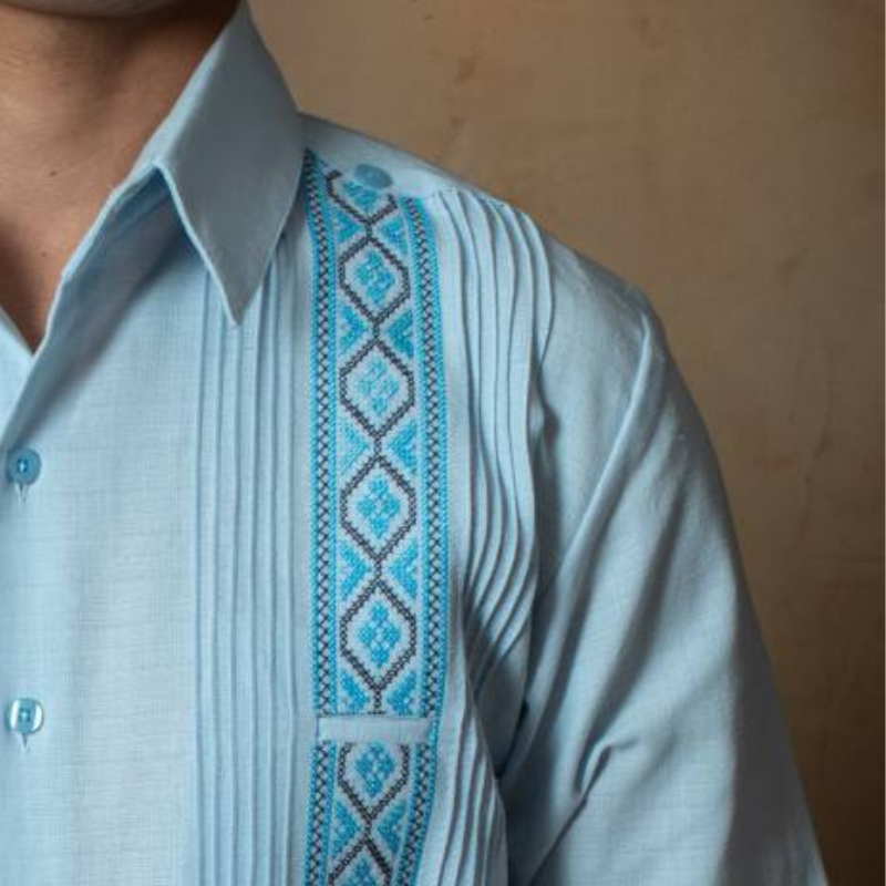 Detalle de los bordados y pliegues de la guayabera azul cielo para hombre.