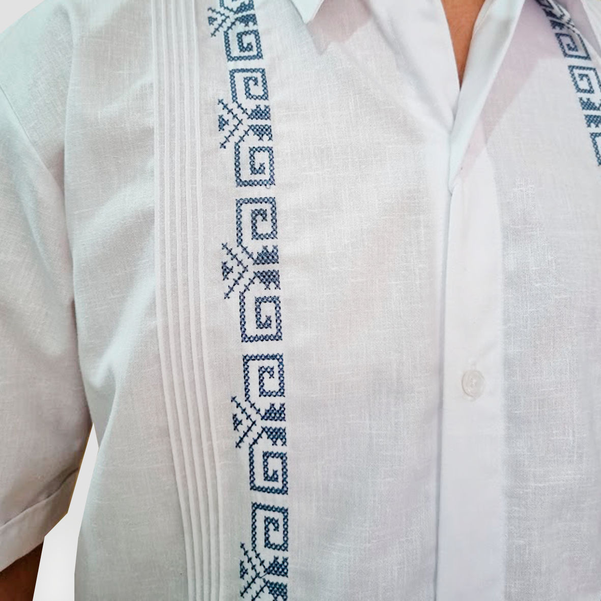 Detalle frontal de bordado azul en guayabera de lino