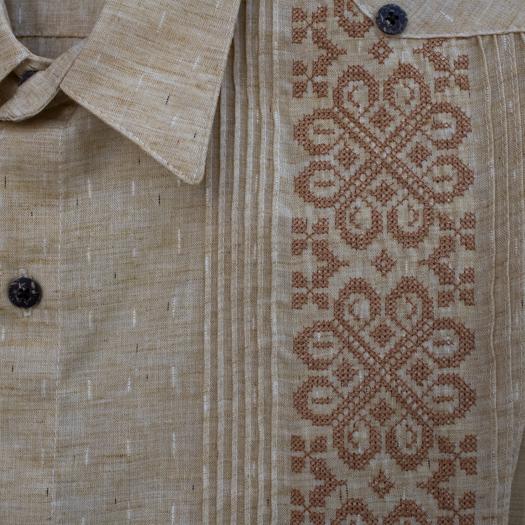 Detalle frontal de bordado mexicano en guayabera beige