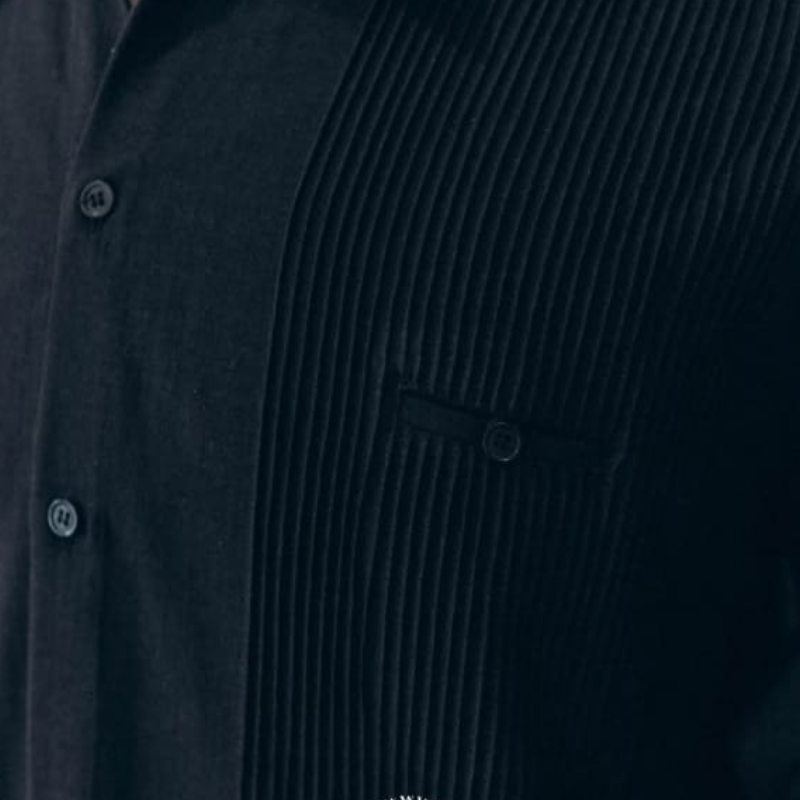 Guayabera presidencial azul marino doblada, mostrando textura de algodón y diseño clásico de manga larga.