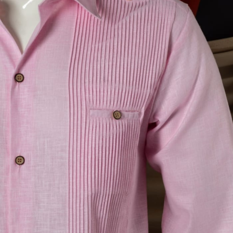 Guayabera presidencial rosa doblada, mostrando textura de algodón y bordado fino de estilo caribeño.