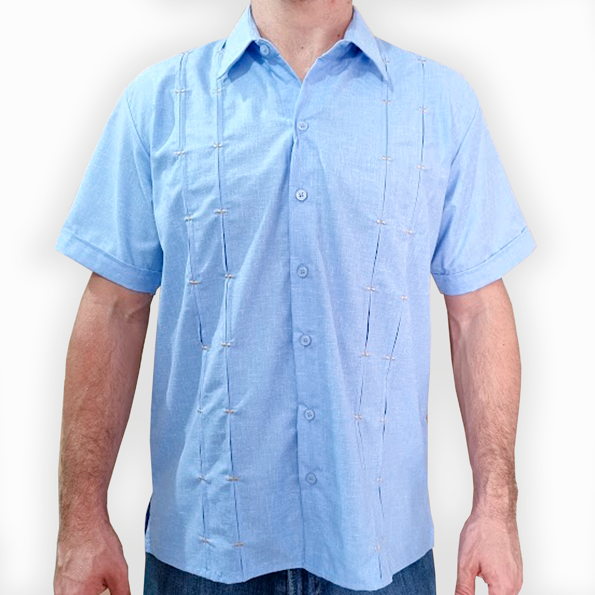 Hombre luciendo una camisa guayabera azul claro en evento al aire libre

