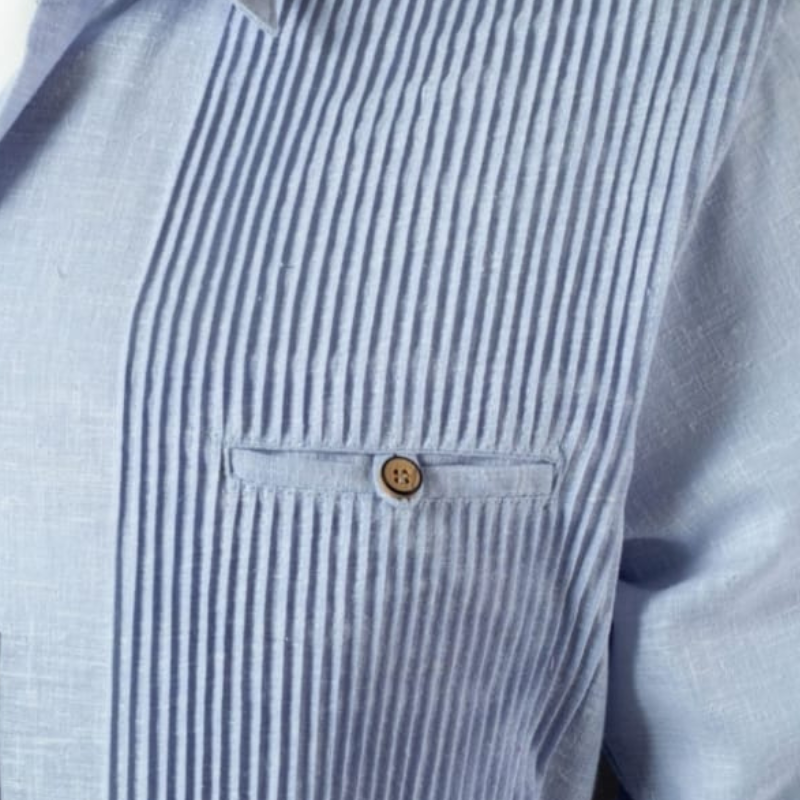 Hombre vistiendo guayabera presidencial azul claro en boda caribeña, combinada con pantalón blanco y mocasines beige.