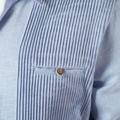 Hombre vistiendo guayabera presidencial azul claro en boda caribeña, combinada con pantalón blanco y mocasines beige.