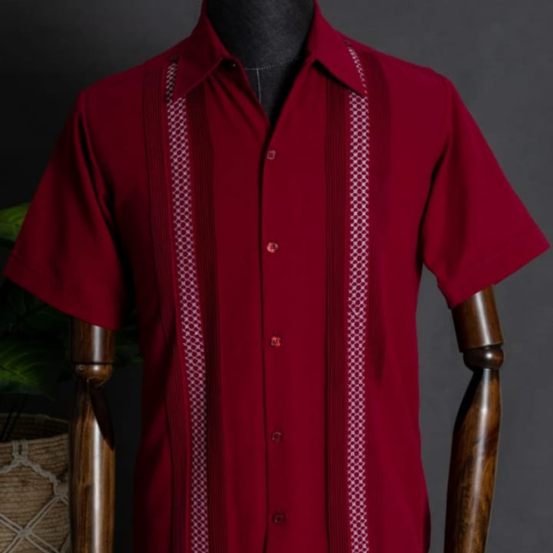 Modelo usando guayabera roja de manga corta con pantalones beige.